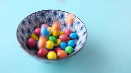 Zeitlupe beim Fallenlassen mehrfarbiger Bonbons in einer Schüssel