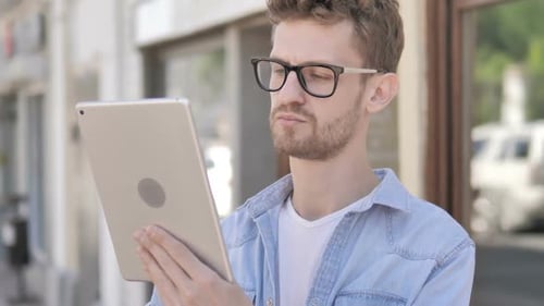 Young Adult Using Tablet Outdoors in Urban Setting