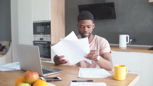 Young Adult Working at Table with Laptop at Home