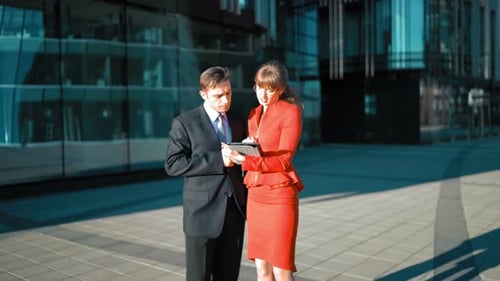Business Professionals Discussing Data on a Tablet Outside
