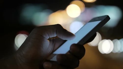 Hand Using Smartphone at Night in the City