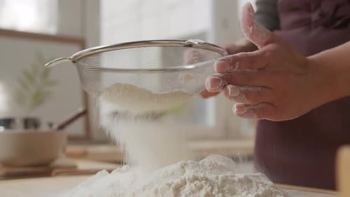 Hands Sifting Flour in a Kitchen