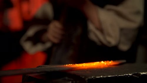 Blacksmith Shaping Hot Metal with Hammer on Anvil