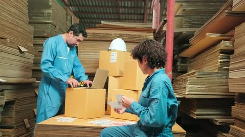 Zwei Mitarbeiter überprüfen mit einem Barcodescanner den Bestand der Bestellungen im Paketlager.