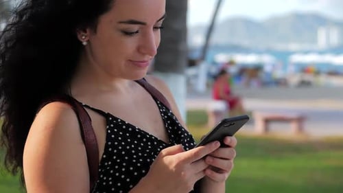 Woman Using Smartphone Near Beach on Sunny Day