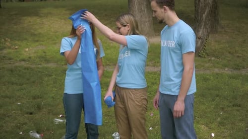 Portrait of Positive Young Volunteers Sharing Garbage Bags for Trash Collection in Summer Park