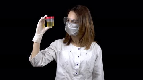 Young Woman Doctor Checks Urine Tests. A Woman Examines a Test Jar, Then Shows a Thumb Up. Positive
