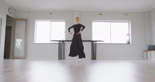 Caucasian female ballet dancer practicing ballet during a dance class in a bright studio