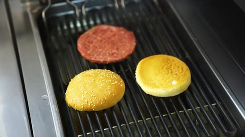 Chef preparing burgers at kitchen. Mixed american barbecue food on hot grill