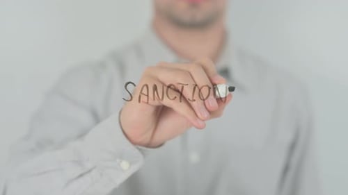 Person Writing Sanctions on Clear Surface with Marker