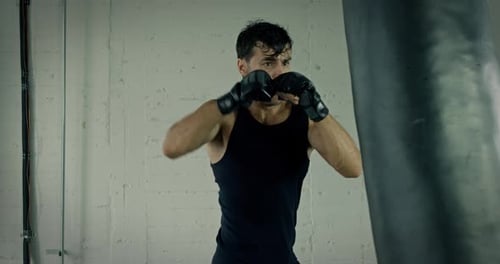 Athletic Man Training Boxing on Punching Bag