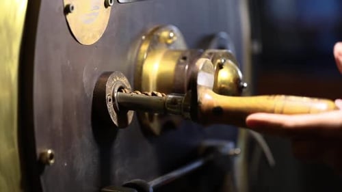 Hand Opens Coffee Roaster Valve to Release Beans