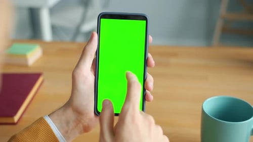 Close-up of Human Male Hand Touching Smartphone with Green Mock-up Screen