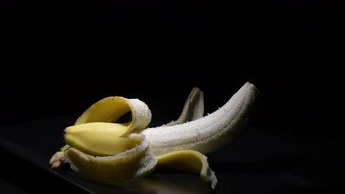 Peeled Banana on a Plate Against Black Background