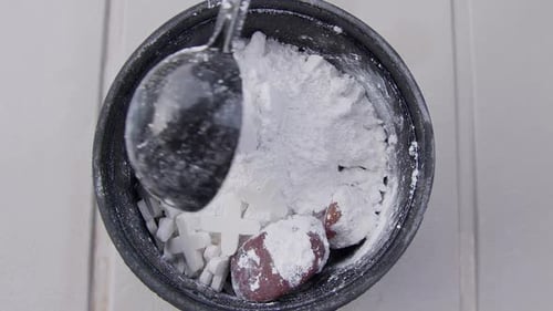 Scoops of polishing grit added to tumbling barrel with rocks
