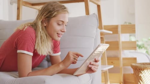 Woman Relaxes on Sofa Using Tablet Device