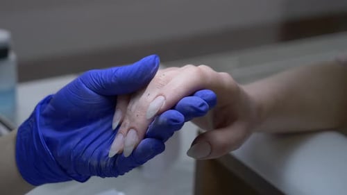 Manicurist Applying Artificial Nails in a Salon