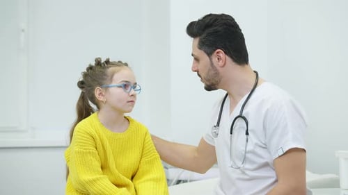Caring Doctor Talking to Young Patient at Clinic