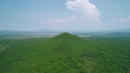 Aerial View of an Endless Geen Forest and a Hill Against the Blue Sky with Clouds