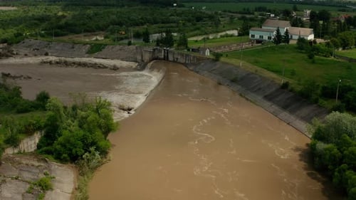 Drohnen-Luftaufnahme. Flusswasser bewegt sich nach schweren Überschwemmungen und Regenfällen mit einem wassergefüllten Damm nach unten
