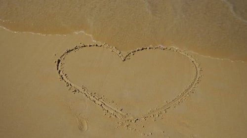 Sea Wave wäscht ein bemaltes Herz auf den Sand