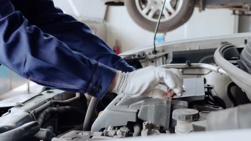 Automechaniker schraubt die Mutter am Automotor ab