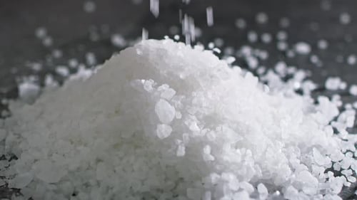 Close up video of salt grains in the air on dark background. Shot with RED helium camera in 8K