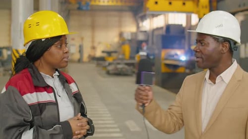 Une travailleuse donne une interview à un journaliste de télévision dans une usine