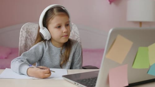 Child Wearing Headphones Studies at Laptop at Home