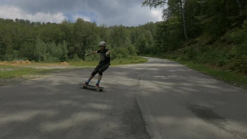 Joven haciendo longboard en la carretera