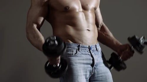 Hombre atlético de potencia guapo con mancuerna. Culturista fuerte con paquete de seis, abdominales y hombros perfectos