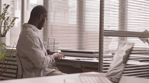 Man Analyzes Documents at Desk in Bright Office