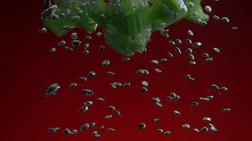 Celery Pieces Splashing into Water with Bubbles
