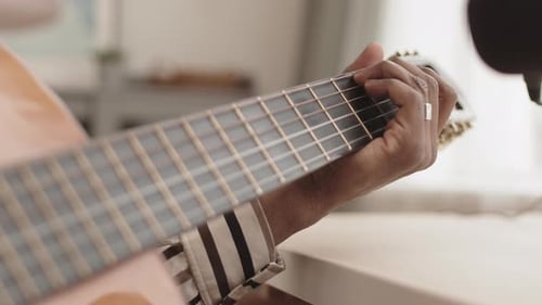 Hand Playing Acoustic Guitar Indoors During Daytime