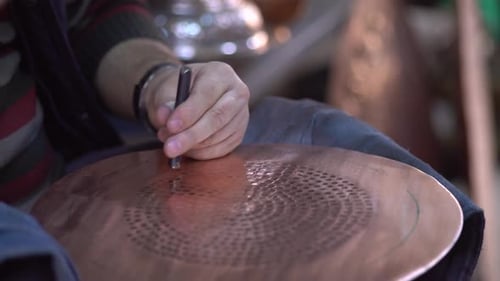 Craftsman Creating Copper Design with Hammer and Stylus