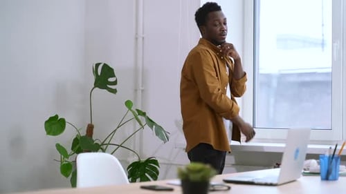 Man Looking Out Window and Sitting at Desk with Laptop in Home Office Spbas