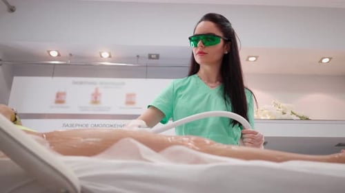 Technician Performing Laser Treatment on Patient's Legs