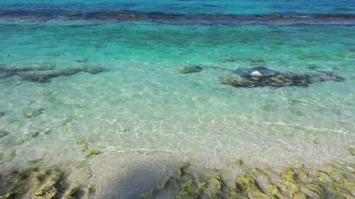 Natural fly over travel shot of a white paradise beach and aqua blue water background in 4K