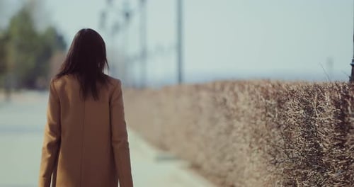Brunette Woman Walks Along a Park Path in Early Spring