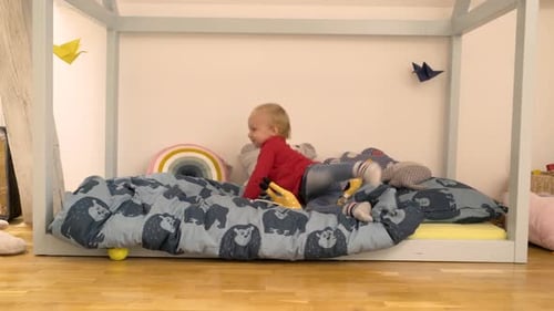 Adorable infant son playing alone on a bed at children room.
