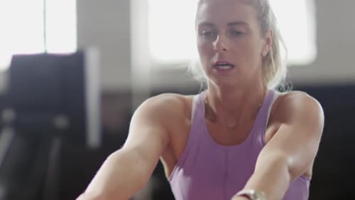 Front view athletic Caucasian woman exercising on a rowing machine
