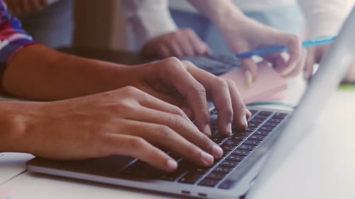Hands of office workers typing on laptop keyboard and the hands of a woman with a calculator