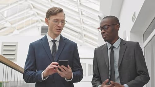 Businessmen Discussing Technology in Modern Office Building