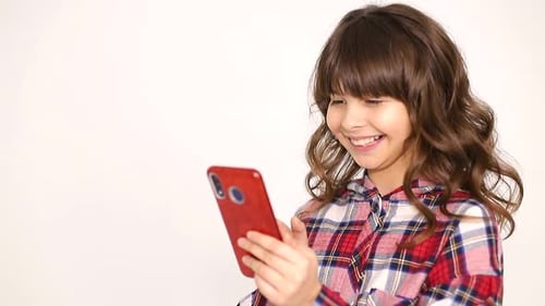 Girl Smiling While Using a Smartphone Indoors