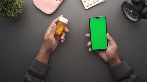 Hands Holding Pills and Phone with Green Screen