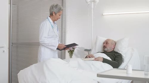 Doctor Visiting Patient Reading in Hospital Bed