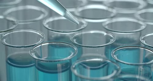 Dropper Dispensing Liquid into Test Tube in Laboratory