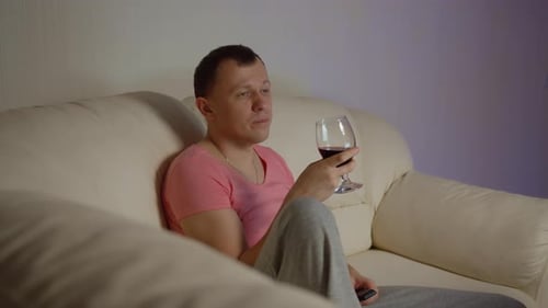 Man Relaxing on Couch with Wine and TV
