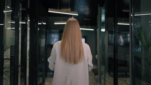 The Camera Follows the Corridor Behind the Redhaired Business Woman