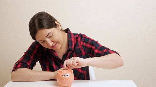 Sly Young Woman Pulls Dollar Banknote Out of Piggy Bank Slot